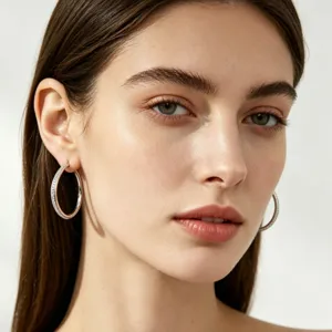 Close-up detail shot of shiny paved crystal hoop earrings worn elegantly by a professional model.