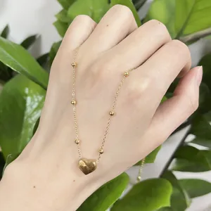 Stainless steel heart pendant necklace detail, featuring elegant gold finish and delicate beaded chain.