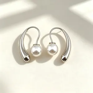 Stainless steel pearl drop earrings close-up, elegant curved design with smooth shiny finish.