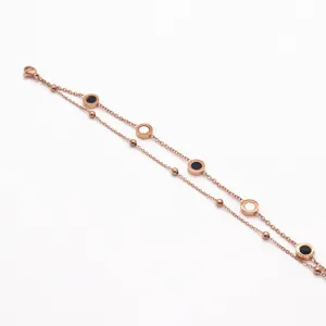 Close-up detail of double layer rose gold stainless steel bracelet with black white inlay circles.