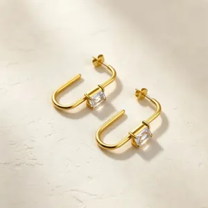Detailed closeup of modern gold-plated stainless steel U-shaped earrings with clear zircon.