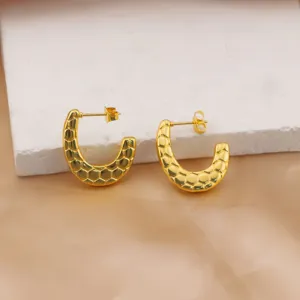 Close-up detail of gold-plated stainless steel earrings with unique geometric scale texture.