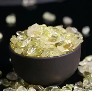 Close-up of natural yellow citrine crystal chips in a dark ceramic bowl for home decor aromatherapy.