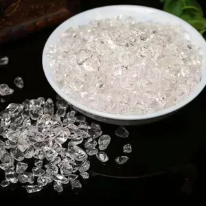 Close up of clear white crystal gravel in a white ceramic bowl on a dark reflective table.