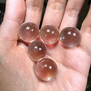 Natural clear white quartz crystal balls held in hand, polished gemstone spheres for home decor.