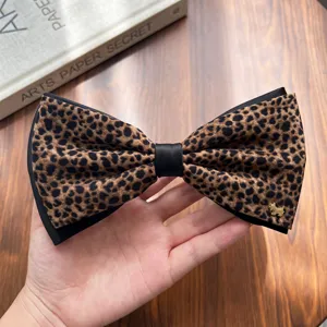 Detailed close-up of the retro leopard print bow hair clip featuring a cute metallic dog charm.