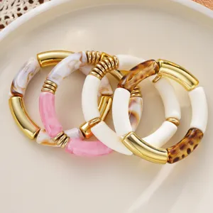 Gros plan détaillé sur les bracelets extensibles superposés en acrylique et métal style rétro.