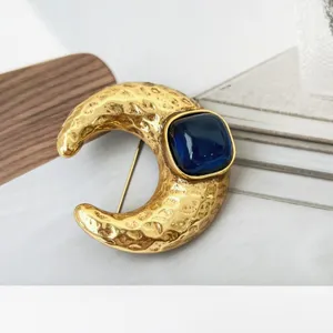 Gedetailleerde close-up van een retro gehamerde maanbroche met donkerblauwe harssteen en stijl.