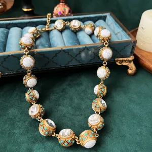Primo piano della collana barocca vintage in metallo dorato, perle bianche e cristalli luminosi.