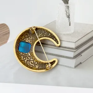 Vintage gouden halve maan broche achterkant detail met blauwe hars steen accessoire.