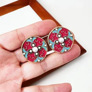 Gedetailleerde close-up van vintage retro paleis stijl geëmailleerde ronde oorbellen.