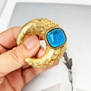 Gedetailleerd shot van vintage gehamerde maanvormige broche met blauwe hars steen accent.