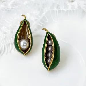 Detailopname van vintage groene emaille erwt peul parel oorknopjes met asymmetrisch ontwerp.