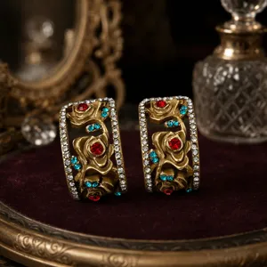 Detailaufnahme vintage 3D geprägter Rosenohrringe in Gold mit Strass und bunten Kristallen.
