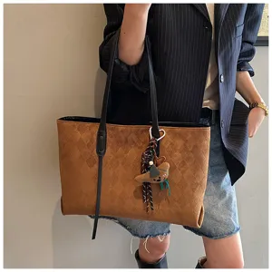 Retro brown tote bag detail showing textured diamond pattern and cute pendant accessory.