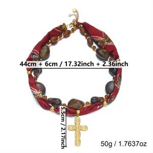 Vista detallada del collar con cruz de acero inoxidable vintage con pañuelo de seda rojo.