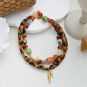 Collar de tela con estampado de leopardo, cuentas acrílicas y dijes de peces dorados.