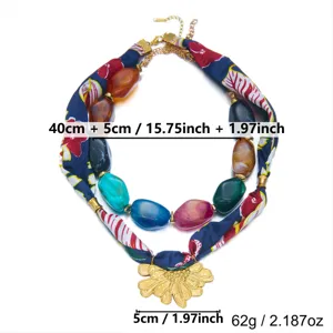 Collar multicapa de pañuelo de seda y cuentas acrílicas con colgante de flor dorada.