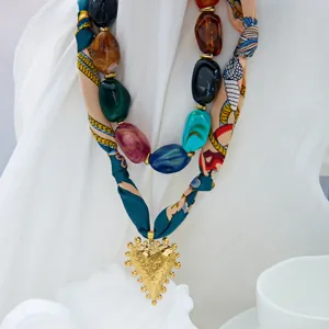 Vista detallada del collar de bufanda de seda con cuentas acrilicas multicolores y dije de corazon.