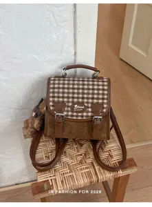 Gros plan détaillé du sac à dos rétro en tweed à carreaux marron avec pendentif ours.