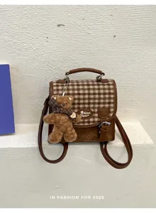Gros plan du mini sac à dos à carreaux marron avec joli pendentif en peluche d'ours.