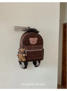 Close-up of brown leopard print PU suede mini backpack with cute bear pendant and bow.