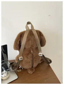 Gros plan détaillé du joli sac à dos en peluche marron posé sur un bureau en bois clair.