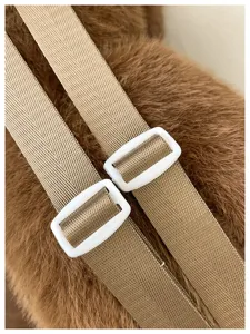 Détail de sac à dos en peluche montrant des bretelles réglables et un tissu résistant.