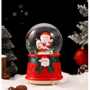 Close-up detail of Christmas snow globe music box featuring Santa Claus and glowing snowman.