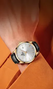 Vue rapprochée d'une montre mécanique pour homme avec boîtier doré et bracelet en cuir noir.
