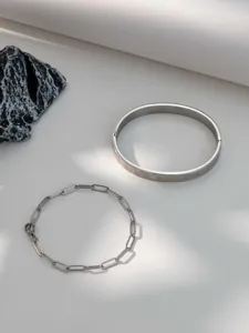 Detail view of silver stainless steel Roman numeral cuff bracelet and paperclip chain set.