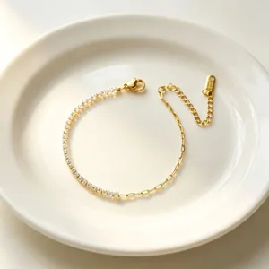 Dettaglio ravvicinato di un elegante bracciale dorato con strass su piatto bianco fine.