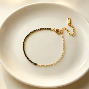 Dettaglio ravvicinato dell'elegante bracciale in acciaio al titanio dorato con pietre verdi.