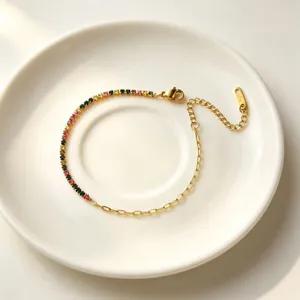 Dettaglio del delicato bracciale dorato con pietre di zircone colorate e catena di estensione.