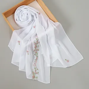 Close-up detail of white chiffon scarf featuring delicate pink floral vine embroidery.