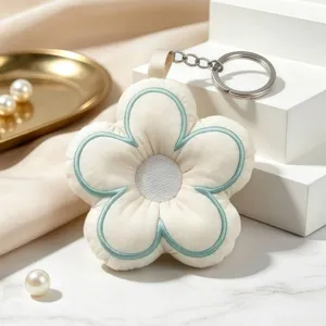 Quilted fabric flower keychain detail showing delicate stitching and metal ring on display staging.