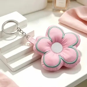 Cute pink plush floral keychain detail, soft stuffed fabric five-petal flower with silver ring.