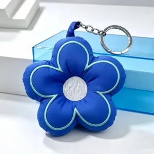 Close-up of the blue five-petal plush flower keychain featuring detailed stitching and metal ring.