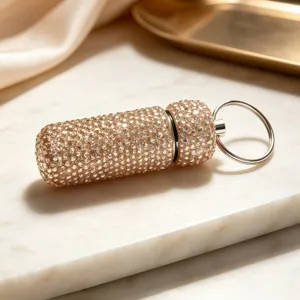 Close-up of a sparkling rhinestone capsule keychain pendant with elegant gold finish.