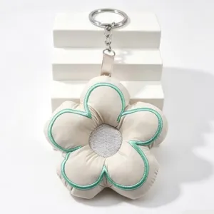 Close-up of cute embroidered stuffed flower keychain with green trim and metal ring.