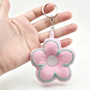Cute pink flower keychain detail, soft plush fabric with green embroidery, metal ring.