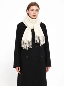 Vue détaillée d'une écharpe d'hiver blanche unie à franges sur un manteau noir.