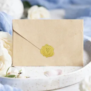 Primer plano detallado de sobre de papel kraft retro con adhesivo de sello de corazón dorado.