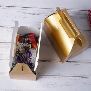 Detalle de caja de pastelería de papel dorado con diseño de asa, ideal para repostería.