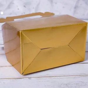 Vista detallada de una caja de pastelería dorada con asa para tartas y postres.