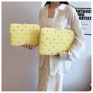 Close-up detail of cute yellow quilted laptop sleeve with colorful embroidered dash patterns.