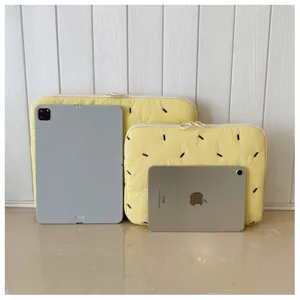Detailed view of cute yellow quilted laptop sleeve with colorful embroidered dash patterns for storage.