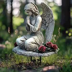 Vue détaillée d'une statue d'ange priant en résine décorée de roses rouges et verdure.