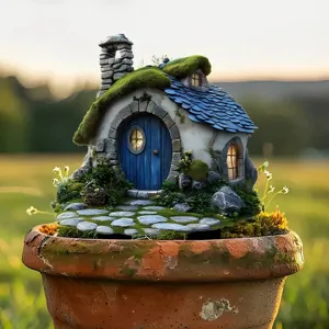 Detailed view of a miniature fairy house sculpture with moss and blue door on a clay pot.