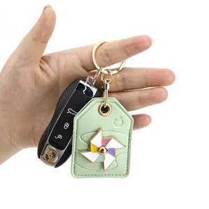 Green leather pinwheel keychain pendant with luxury car key fob charm for daily use.